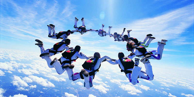 Methodenkompetenz Symbolbild Fallschirmspringer in der Luft, die gemeinsam einen Kreis bilden